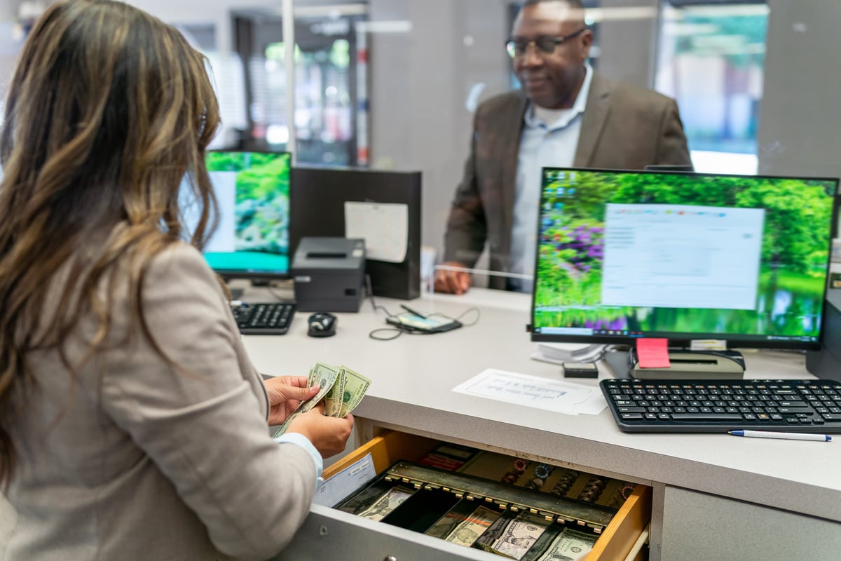 Bank teller counting money for customer